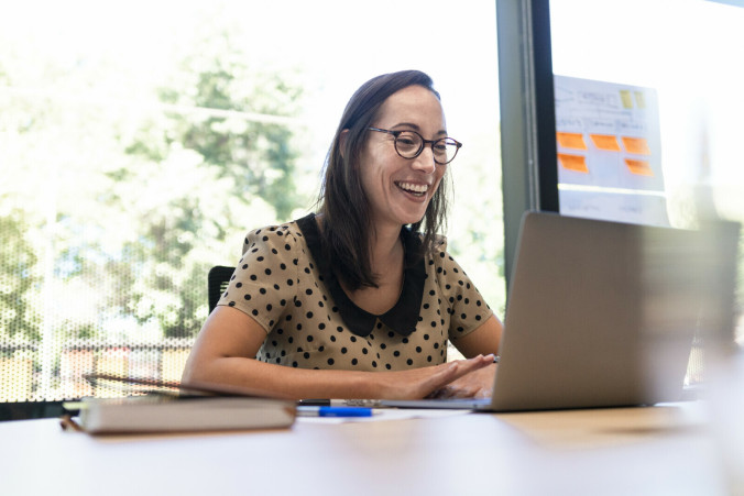 Smiling woman typing on a laptop